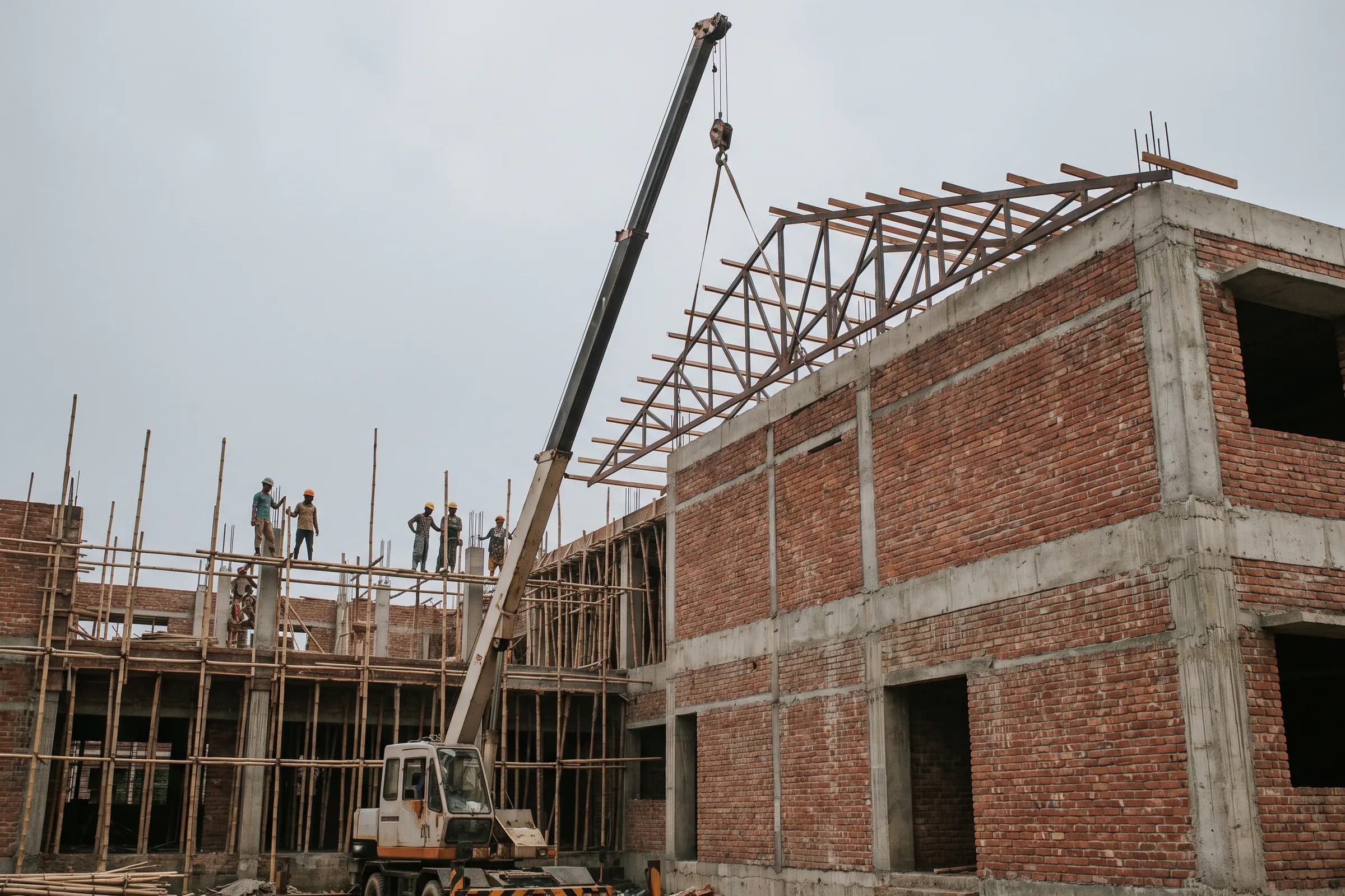 Steel roof trusses being lifted by crane onto the brick walls of the library